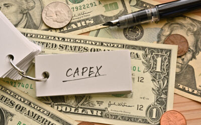 An image of American dollars on a table top. Sitting on top of the dollars is a keyring of small white cards, which is open to show the word 'CAPEX'.