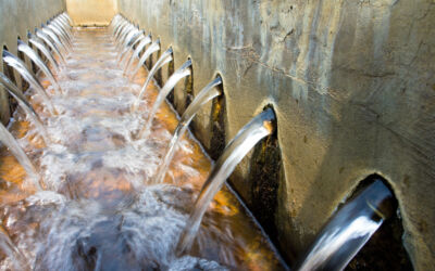 An image of two walls facing each other. There are approx 10 pipes in each wall. Water is gushing out of each pipe into a channel between the two walls.