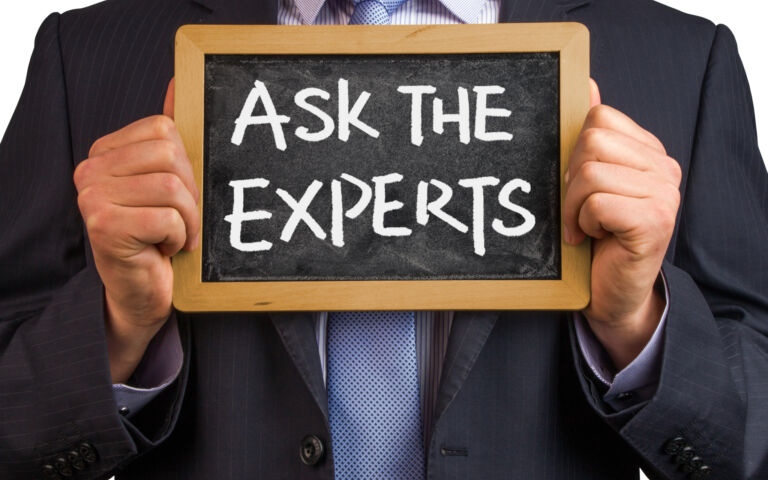 Image of a man in a suit holding a blackboard displaying the chalked words 'Ask the experts'.