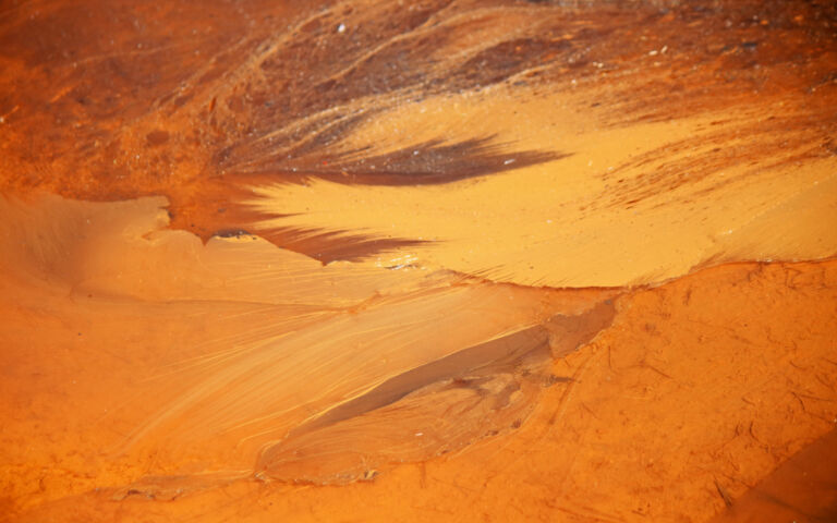 Abstract image of what looks like sand or flowing lava, in different shades of orange.